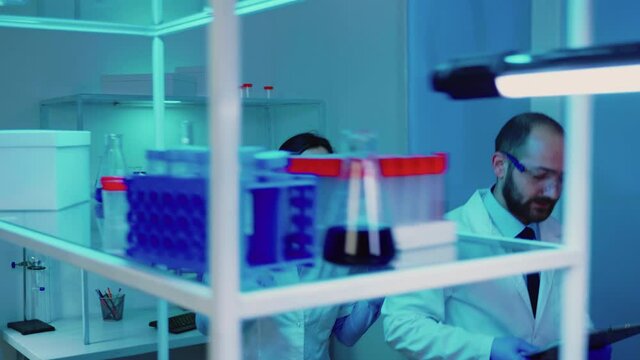 Scientists coworkers working in chemical modern equipped laboratory at night analysing test results. Stuff examining vaccine evolution using high tech researching treatment against covid19 virus