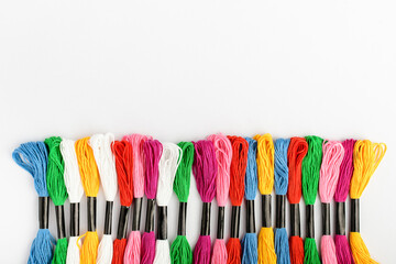 Line with many mixed vivid colored sewing threads for embroidery isolated on a white table, top...
