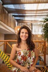 Beautiful woman wearing a dress sitting on a striped hammock