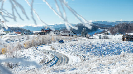 A blue car on winter road in the mountain village