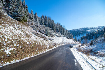 Fototapeta na wymiar Winter road passing through the hills and forest