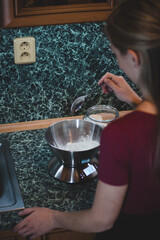 cook weighs the sugar on an electronic scale to determine the exact weight. Adding a sweet flavour to the gingerbread dough. Baking Christmas cookies. Woman with braid adds spoonful of spelt flour