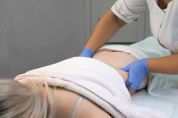 Correction of skin after pregnancy. Doctor is massaging body of woman after injection of ozone gas...