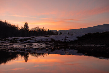 Amazing mountain sunset with reflection in the lake in winter