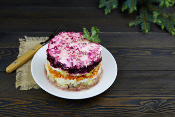 Layered shuba salad. Festive Christmas vegetable salad with fish and boiled vegetables on rustic wooden table. Herring under a fur coat