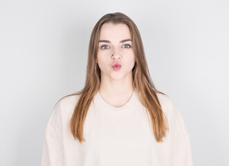 Portrait of lovely girl in casual outfit sending blowing kiss with pout lips looking at camera isolated on white background.