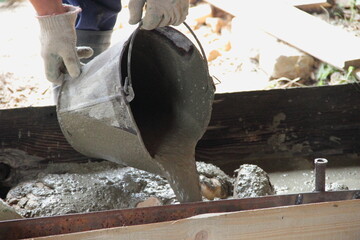Pouring concrete from a bucket of  Foundation floor around the garage observation pit close up of a rural covered industrial construction building