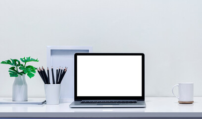 Mockup blank screen laptop with supplies on white wooden table.