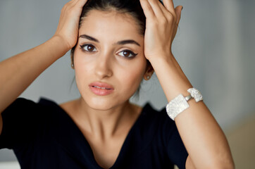 Fototapeta premium beautiful woman model touches her face with her hands on a gray background and evening dress decoration on her hand