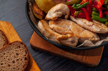 baked chicken, potatoes and vegetables in a cast-iron frying pan.