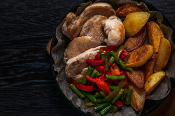 baked chicken, potatoes and vegetables in a cast-iron frying pan.