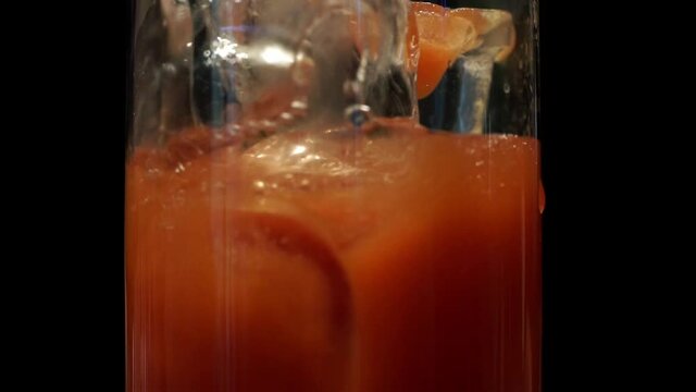 
Making a Michelada cocktail.Tomato juice, ice. Pouring beer. Close up.