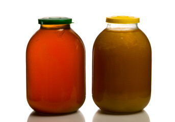Two large glass jars with honey on a white background closed with colored lids