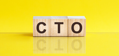 CTO - Chief technical officer - word is made of wooden building blocks lying on the yellow table