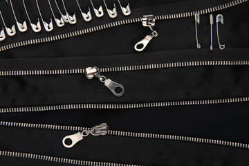 Safety pins and zippers on black fabric. Close up of subculture clothing.