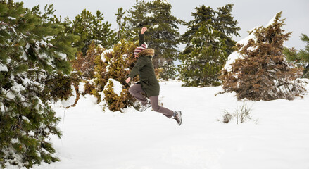 happy young man jumping over snow in the forest in wintertime and have fun with beautiful mountain background.