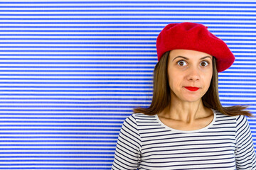 Portrait of woman that looks like she is caught in a lie. She is wearing red beret and striped...