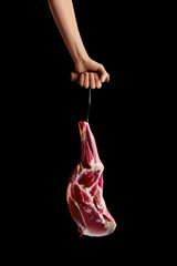 Hand of a butcher holds raw leg of lamb