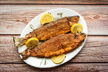 Fried fish with lemons on white dish