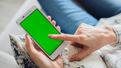 woman is relaxing on comfortable couch and using smartphone at home