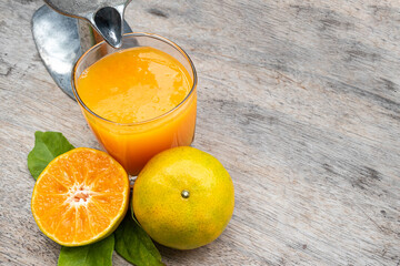 Orange juice in glass and fresh citrus around with Juicer hand press squeezer fruit on wood table....