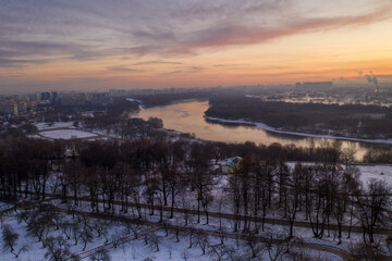 Fototapeta na wymiar panoramic view of the park in the city on the river bank with old buildings at sunrise in winter filmed from a drone