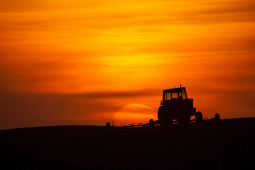Old tractor and cultivator at sunrise