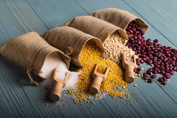 studio lighting. Retro style wooden background. There are cereals on it. Red beans, millet, pearl barley, sugar and a spice spoon next to it. Close-up