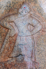 Obraz premium Hampi, Karnataka, India - November 4, 2013: Mural sculpture on brown-gray stone at Royal Enclosure. Closeup of mural sculpture of bearded man leaning on cane. Red dot on forehead.