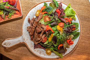 Roast beef slices with vegetables on a white dish. Look up