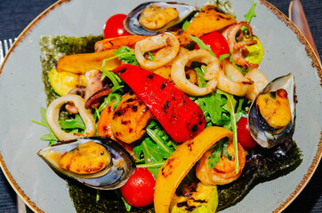 Seafood salad, shrimps, mussels, grilled vegetables are on a platter. Restaurant menu