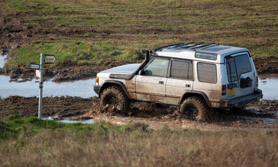 Obraz na płótnie Canvas old silver land rover discovery series II 4x4 wading through muddy water