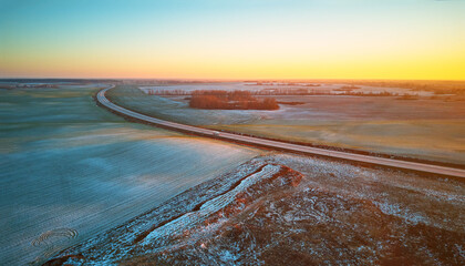 Winter green Agricultural field winter crops under snow panorama. Highway December sunset Aerial scene.