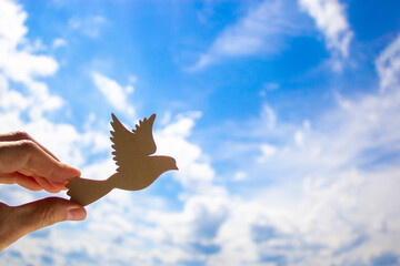 Man hand holding wooden bird on cloud sky background. The development of the imagination, copy space.