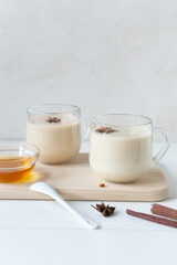 Two glass cups of Masala tea with spices and honey on a white background. Indian traditional beverage. Vertical orientation. Copy space.