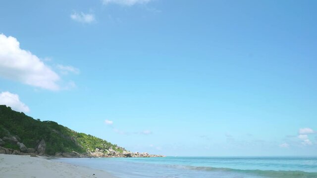 Exotic beach by the ocean with rolling waves on the sandy shore and blue sky. 