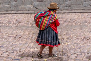 Peru, woman in her colourful traditional dress is walking in the street. - obrazy, fototapety, plakaty