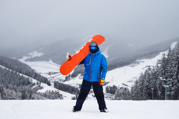 Fototapeta na wymiar The guy hold on the shoulder orange snowboard in winter