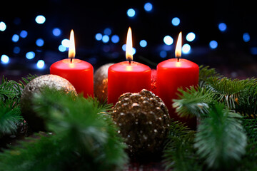 Lighted red candles surrounded by holiday decorations.