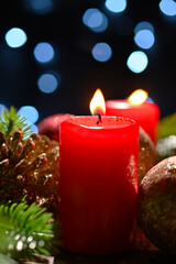 Lighted red candles surrounded by holiday decorations.