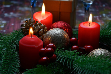 Lighted red candles surrounded by holiday decorations.