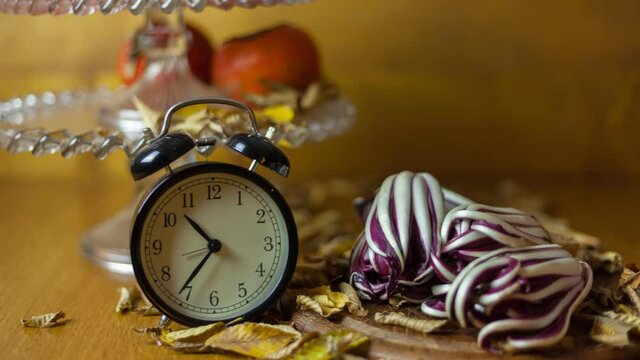 Alarm clock timelapse with typical autumn products in the background such as radicchio di Treviso and persimmon. Wodden background