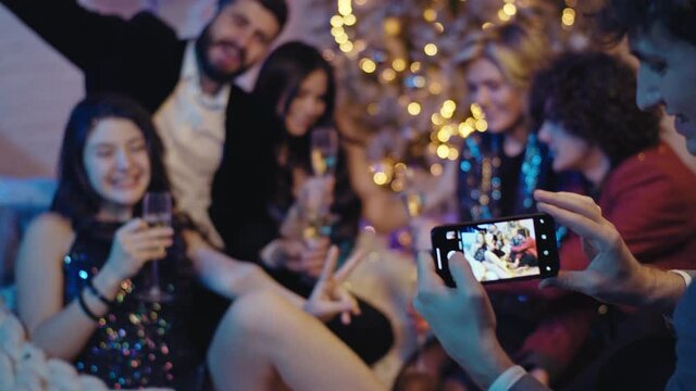 Posing young people at Christmas party a guy taking pictures with a phone for memories they feeling so excited and happy enjoying the time together