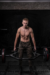 Fototapeta na wymiar an athlete with a muscular torso raised and holds a square barbell