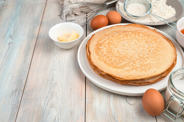 Stack of fried pancakes, butter, eggs and flour on a light background. Side view, with space for writing. The concept of cooking, recipes, Mardi Gras.