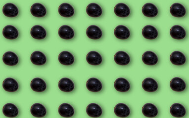 Pattern with black grapes with shadow on a green background.