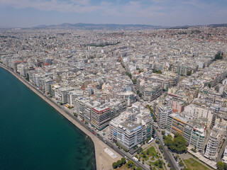 Aerial drone view of iconic historic landmark - old byzantine White Tower of Thessaloniki or Salonica with traditional tourist boats travelling Thermaikos gulf, North Greece