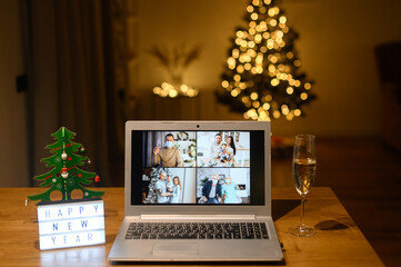 Celebrating Christmas day on the distance. Virtual meeting with a family, video call on the laptop. Webcam screen with a shots of different people in the decorated living room