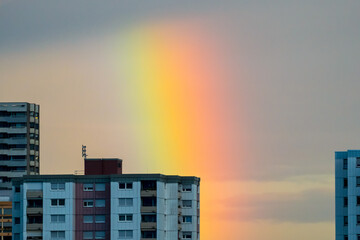 Multicolored rainbow segment behind city buildings