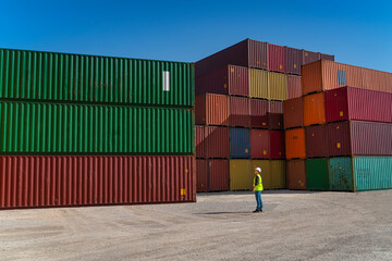 Engineer man with white safety helmet and worker west checking cargo freights in front of colorful...